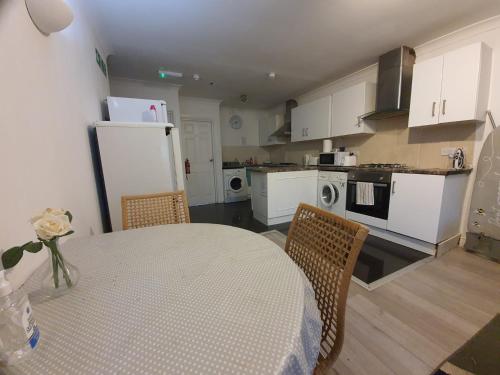 a kitchen with a table and a kitchen with white appliances at Eastwood Rooms in Goodmayes