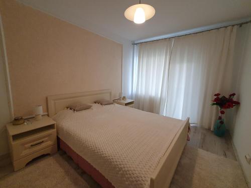 a bedroom with a white bed and a window at Suceava apartment in Suceava