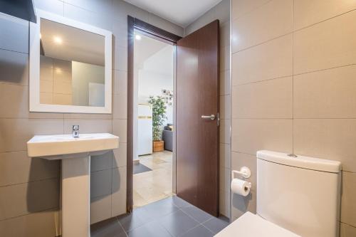 ein Badezimmer mit Waschbecken, Toilette und Spiegel in der Unterkunft Trinisol Apartment Sea Views 6E Levante Beach in Benidorm