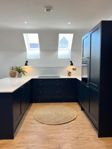 a kitchen with black cabinets and white counter tops at The Hayloft in Sudbrooke