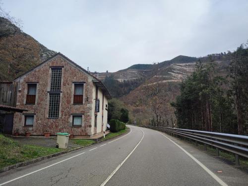 an empty road next to a building on the side of a mountain at La Salmonera Cangas de Onís in Caño