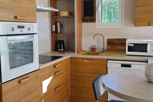 uma cozinha com electrodomésticos brancos e uma mesa em Au cœur du Vallon de Laghet, Maison Indépendante em La Trinité
