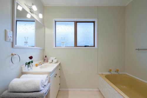 a white bathroom with a tub and a sink and a bath tubermott at The waterfront 361-Family retreat with Netflix Skysport Air conditioner in each bedroom in Auckland