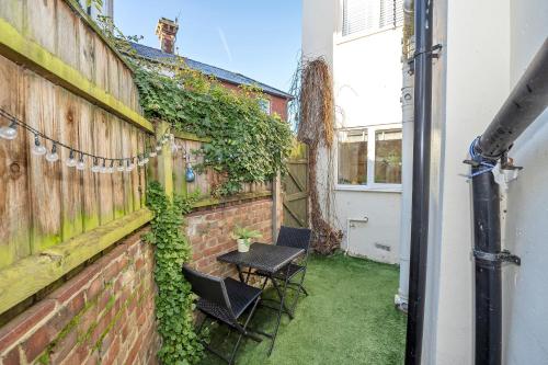 a patio with two chairs and a table with ivy at 42 Church Row - 2 beds and 2 bathrooms in Bury Saint Edmunds