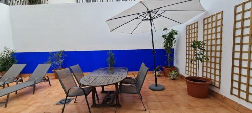 a patio with a table and chairs and an umbrella at Apto T Patio Sevillano - Garaje privado in Seville