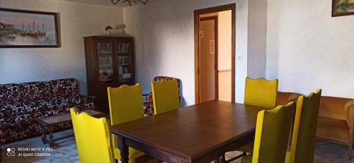 a dining room with a wooden table and yellow chairs at Etablissement commun avec chambre privé tranquille avec jardin a 10 min a pied de la gare de Fleury-les-Aubrais et 2 min d Orléans in Fleury-les-Aubrais
