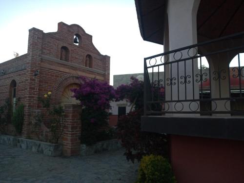 a brick building with purple flowers next to a balcony at Hotel Hacienda San José in San Francisco del Rincón