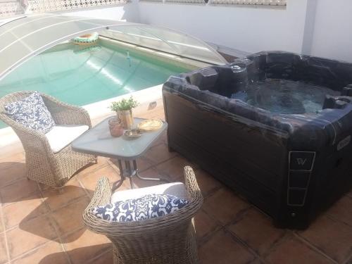 een hot tub met stoelen en een tafel naast een zwembad bij Tienda linda in Puebla de Vallbona