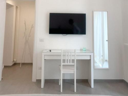 a white desk with a chair and a television on a wall at Donna Anna in Polignano a Mare