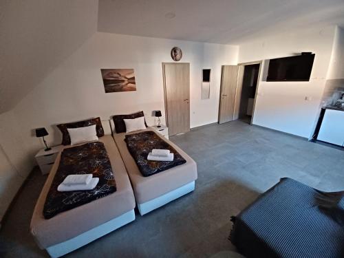two beds in a room with a tv and a room with at Apartmani Marijamagdalena in Gračac