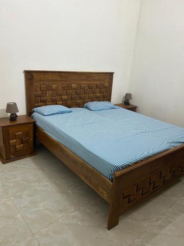a bedroom with a bed with a blue comforter and two tables at Villa Kayus - Toubab Dialaw in Rufisque