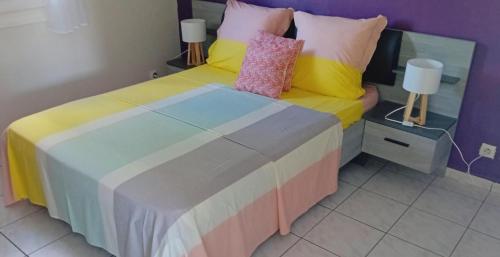 a bedroom with a bed with colorful sheets and pillows at gîte La Cannaie in Port-Louis