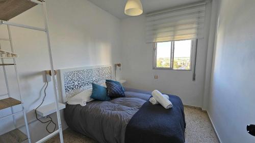 a bedroom with a bed with blue sheets and a window at Karma loft en la playa in Sanlúcar de Barrameda