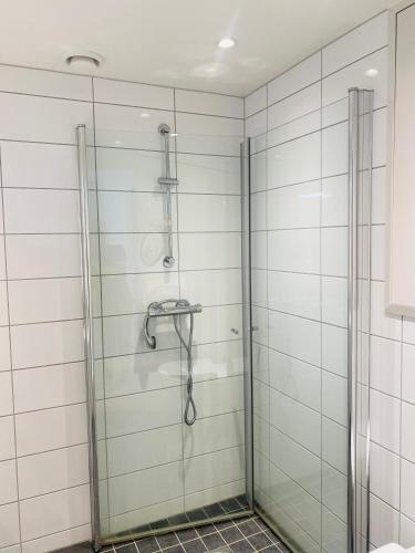 a shower in a bathroom with white tiled walls at Leilighet ved Slottsfjellet in Tønsberg