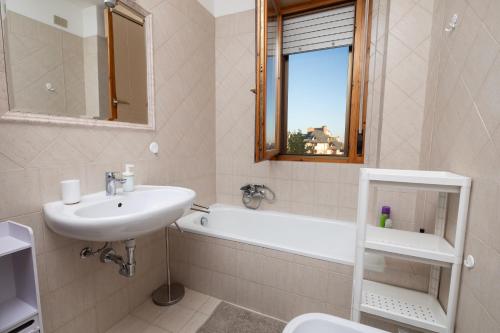een badkamer met een wastafel, een bad en een toilet bij Apartment Forum IV in Assago