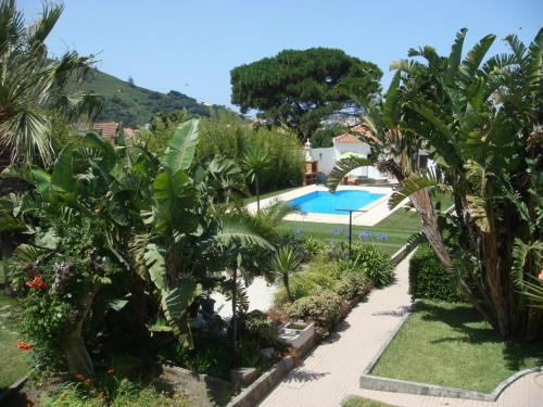 a garden with a swimming pool and palm trees at Casa De Hospedes Flor Do Jardim in Malveira
