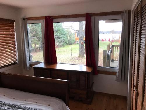 a bedroom with three windows and a bed and a desk at Le gîte du Lac à la Tortue in Herouxville