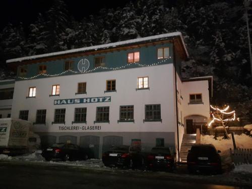 a large white building with cars parked in front of it at Haus Hotz Apart Talblick in Grins