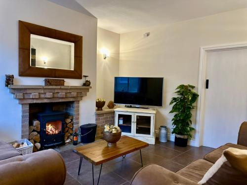 a living room with a fireplace and a flat screen tv at Fallow Cottage, 3 Bedrooms, Woodburner - Heart of Stamford by Belmont Places in Lincolnshire