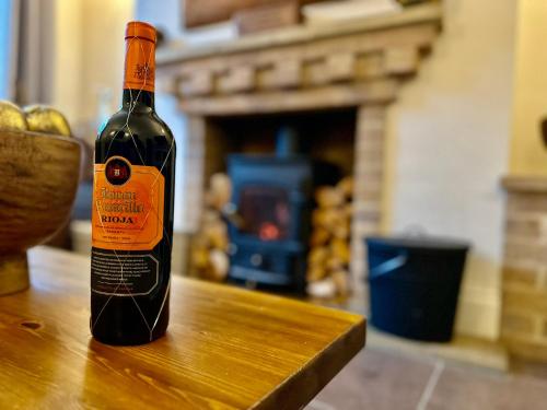 a bottle of wine sitting on top of a wooden table at Fallow Cottage, 3 Bedrooms, Woodburner - Heart of Stamford by Belmont Places in Lincolnshire