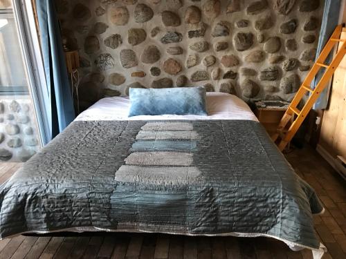 a bed in a room with a stone wall at Le gîte du Lac à la Tortue in Herouxville