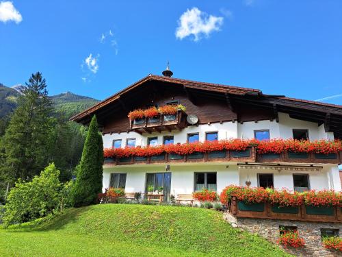a house with red flowers on the side of it at Hotel garni Landhaus Bürtlmair in Hinterstoder