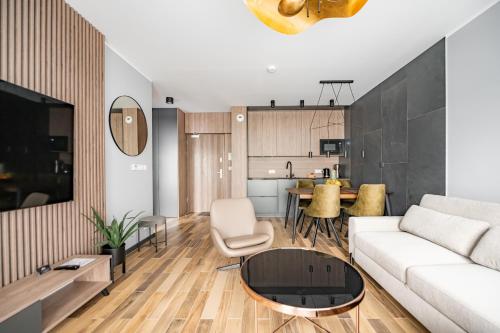 StoneHill24 - Apartament & Spa في شكلارسكا بوريبا: غرفة معيشة مع أريكة بيضاء وطاولة