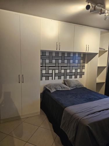 a bedroom with a bed and white cabinets at Apto Barra Olímpica in Rio de Janeiro