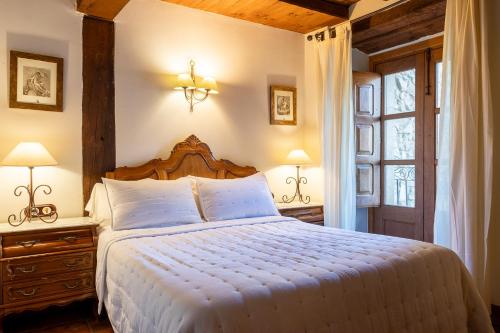 ナバコンセホにあるCasa Rural La Fuente del Jerteのベッドルーム1室(ベッド1台、ランプ2つ、窓付)