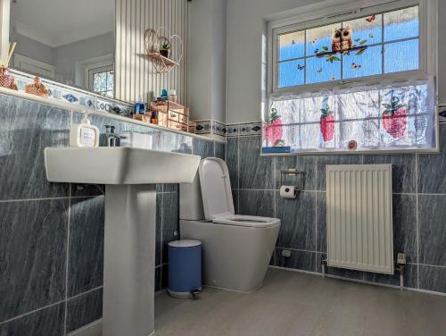 uma casa de banho com um lavatório, um WC e uma janela. em FINN VILLAGE "Raspberry Cottage" Private Garden, 6-seater Hot Tub, Firepit & Pizza Stove em Glasgow