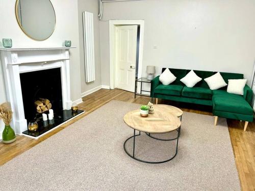 Una sala de estar con un sofá verde y una mesa. en Foyleview Villa, en Derry Londonderry