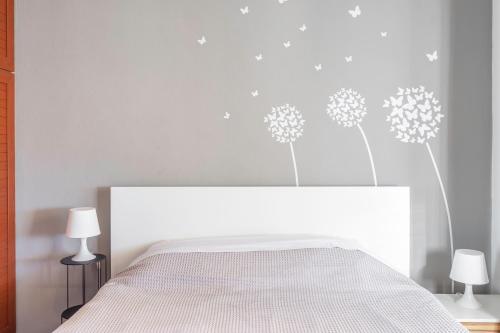 a bedroom with a white bed with dandelions on the wall at The Owl - Stylish Penthouse - Gazi 1BDRM in Athens