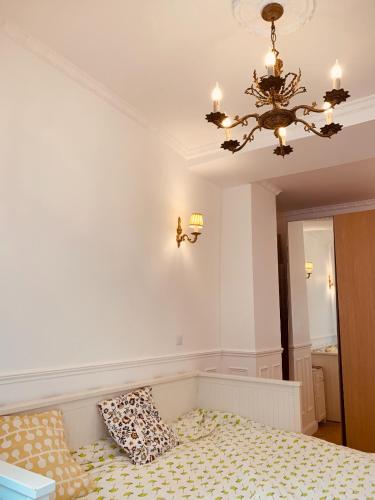 une chambre avec un lustre et un lit avec des oreillers dans l'établissement Parisian style Appartment Private room with Shared bathroom near Bastille and Gare de Lyon, à Paris