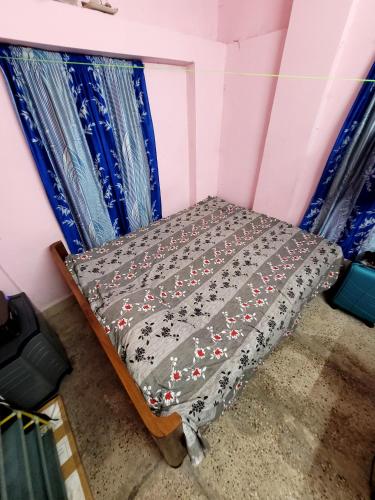 Cama pequeña en habitación con cortinas azules en holiday Villa, en kolkata