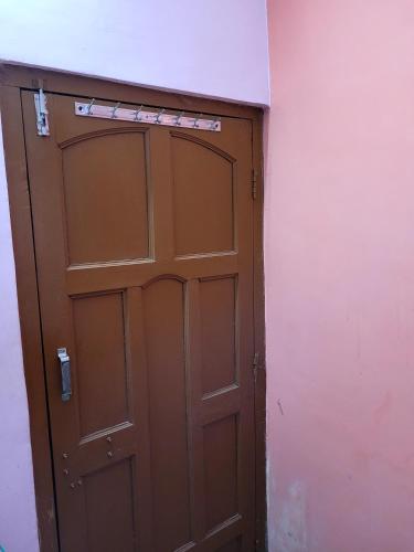 una puerta marrón en una habitación con una pared rosa en holiday Villa, en kolkata