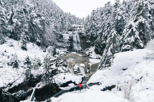 a person standing in the snow next to a waterfall at T2 Pyrénéen in Pierrefitte-Nestalas