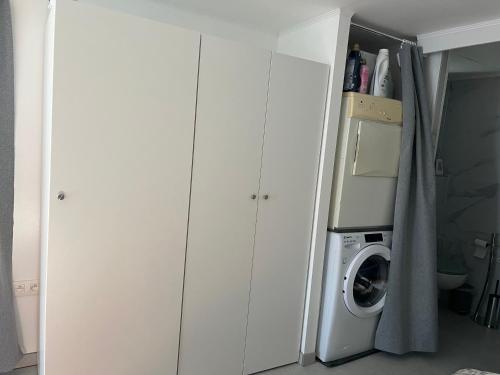 a laundry room with white cabinets and a washing machine at Studio renové rdc terrasse wépion (Namur) in Namur