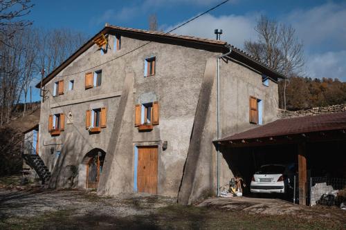 a large stone building with a car parked in front of it at Mas el Cornut in Campdevánol