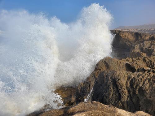 a wave crashing on the rocks in the ocean at imsouane bleu bay house in Imsouane