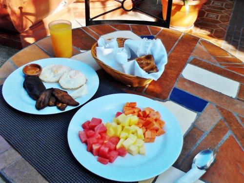 two plates of food on a table with fruit on them at Hotel Las Camelias Inn by AHS in Antigua Guatemala