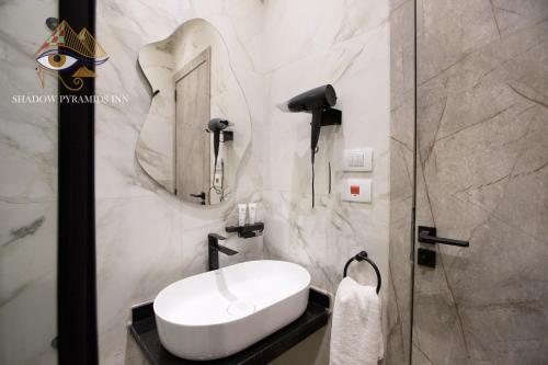 a bathroom with a white sink and a shower at Shadow Pyramids Suites and Jacuzzi in Cairo