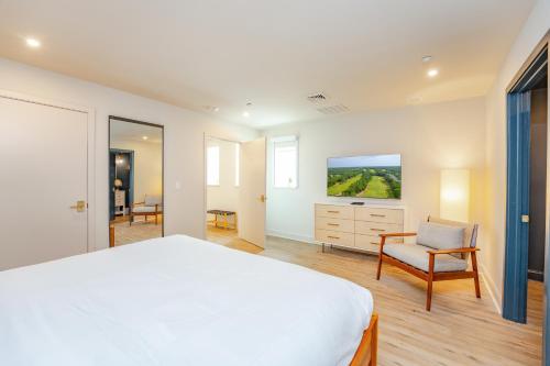 a bedroom with a white bed and a chair at The Inn at LBI National Golf & Resort in Little Egg Harbor Township