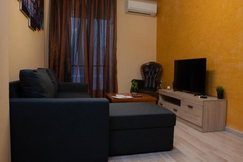 uma sala de estar com um sofá azul e uma televisão em Galerius Palace em Tessalônica