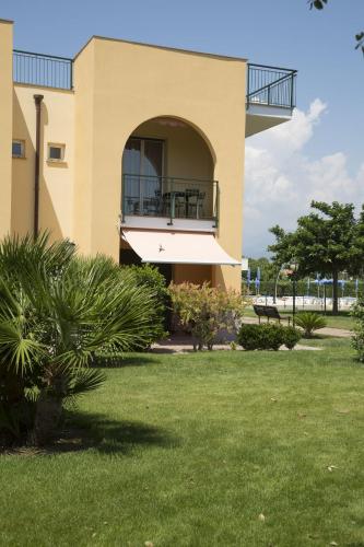 a building with a balcony and a grass yard at Residence Borgomare in Albenga
