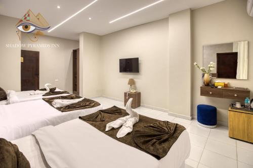 a hotel room with two beds and a tv at Shadow Pyramids Suites and Jacuzzi in Cairo