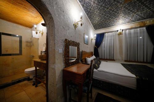 a bedroom with a bed and a desk and a sink at Cappadocia Nar Cave House & Swimming Pool in Nevsehir
