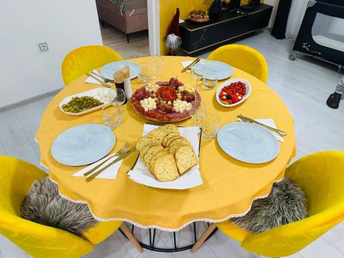 a yellow table with plates and food on it at Apartman Jovičić in Bjelovar
