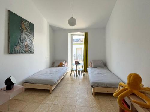 1 Schlafzimmer mit 2 Betten, einem Tisch und einem Fenster in der Unterkunft Design & art, patio with orange tree, near Seville in Carrión de los Céspedes