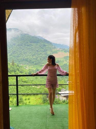 a woman standing on a balcony looking out of a window at Eco cottage sunrise merisi in Merisi
