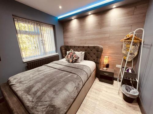 a bedroom with a large bed and a wooden wall at MODERN SUITES -5 Bedroom House- With FREE PARKING Birmingham city in Birmingham